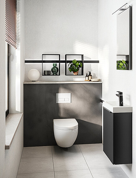 Elegant modern bathroom featuring a wall-mounted toilet, matte black cabinetry with a white countertop, and minimalist decor with green plants.