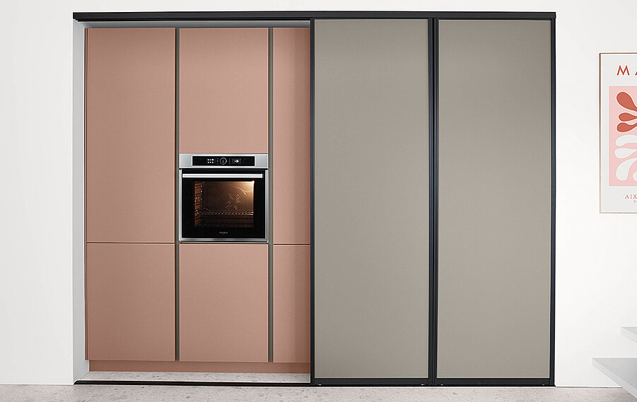 Moderne Küchenschränke mit eingebautem Backofen, präsentieren ein schlankes Design mit rosafarbenen und grauen Schiebetüren und minimalistischem Stil in einem zeitgenössischen Interieur.