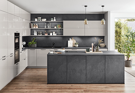 Modern kitchen interior with sleek dark cabinetry, integrated appliances, and a central island, complemented by warm wooden flooring and pendant lighting.