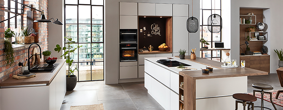 Ruime moderne keuken met strakke apparaten, houten werkbladen en stijlvolle planken, geaccentueerd door natuurlijk licht en warme, uitnodigende tinten.