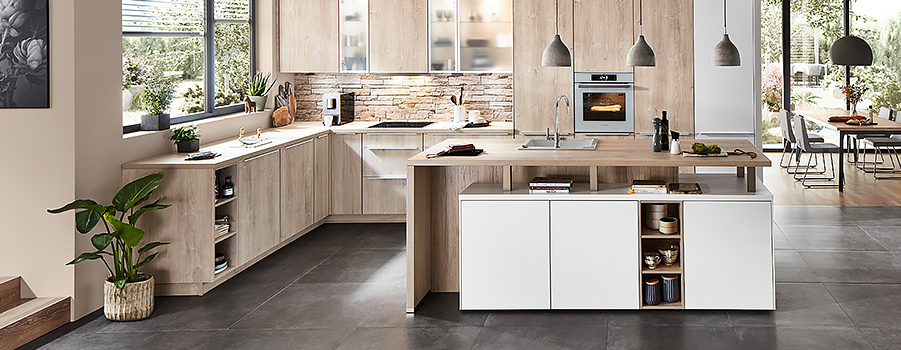 Diseño de cocina moderna con líneas limpias, acentos de madera, electrodomésticos de última generación y una isla central con estanterías abiertas en un interior luminoso y espacioso.