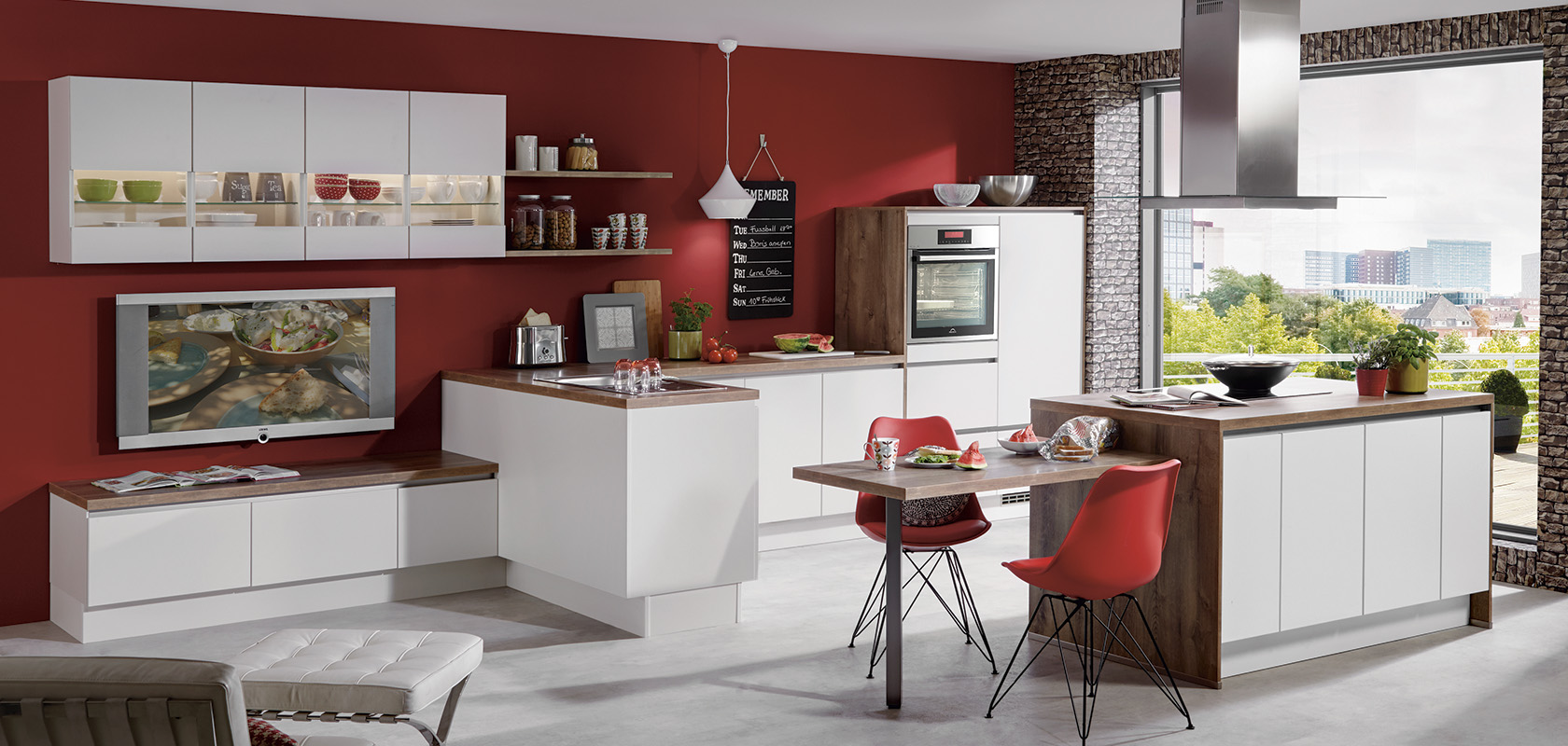 Moderne keukeninterieur met wit modulair kastwerk, rode accentmuren, bakstenen elementen, strakke apparaten en een gezellig eetgedeelte met een schilderachtig uitzicht op het raam.