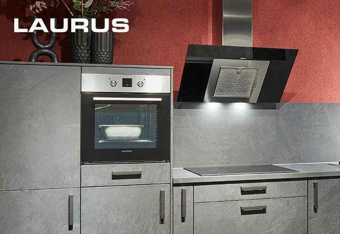 Moderne keuken met een strakke LAURUS oven ingebouwd in donkergrijze kasten met roestvrijstalen handgrepen, onder een zwarte afzuigkap en tegen een rode muur.