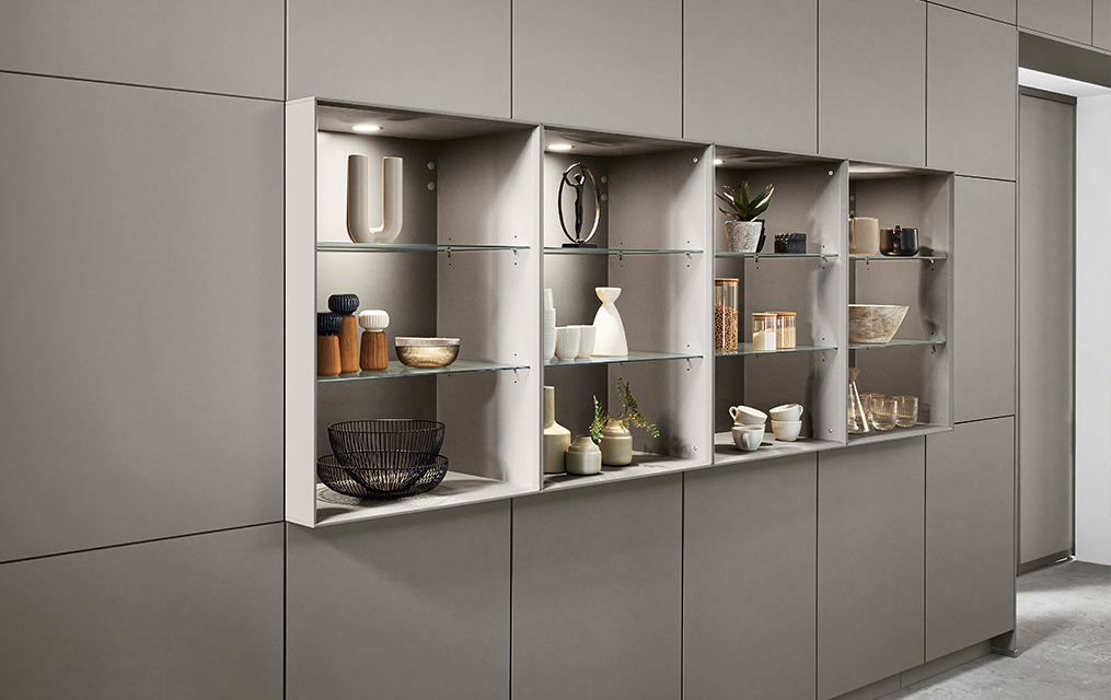 Unidad de estantería minimalista incrustada en una pared gris, mostrando una selección cuidadosamente elegida de objetos decorativos y plantas de interior para un diseño interior moderno y elegante.