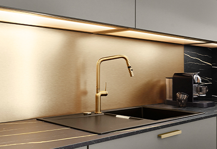 Elegante cocina moderna con un elegante grifo dorado, fregadero integrado e iluminación sofisticada debajo de los gabinetes con lujosos acentos negros y dorados.