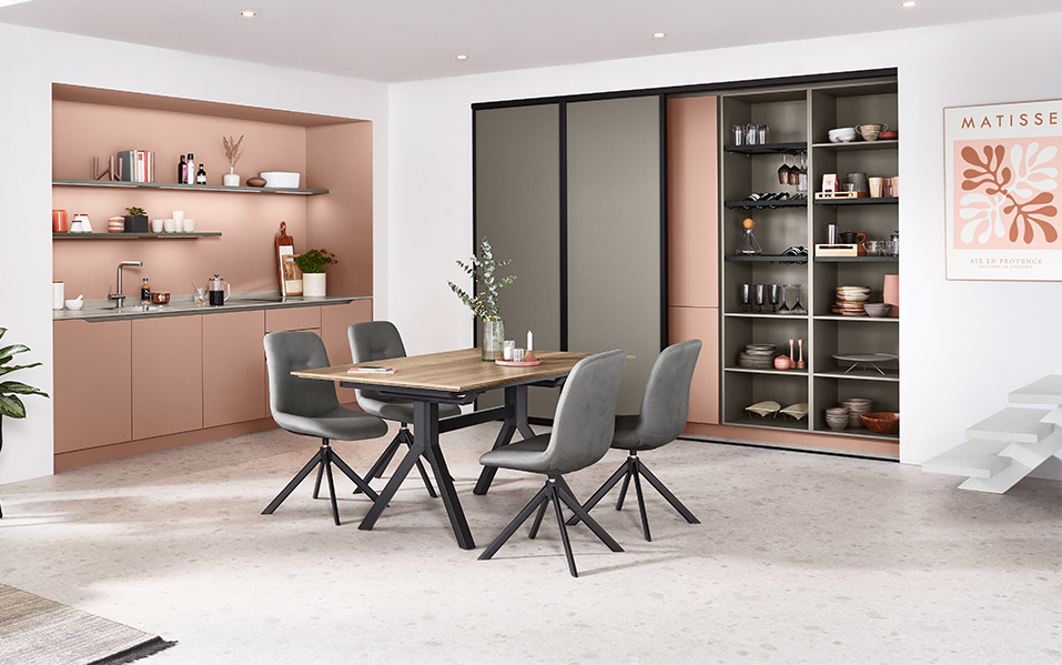 Modern kitchen interior featuring a sleek dining area with stylish chairs, open shelving with decor, and a sophisticated cabinet system against a soft pastel backdrop.