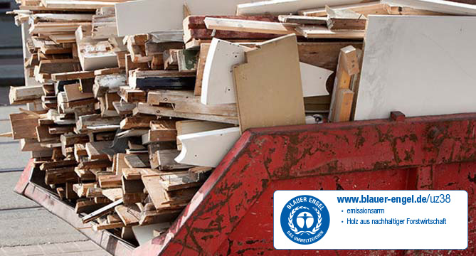 A pile of assorted wooden boards and old furniture pieces thrown into a large red skip, indicating a construction or renovation cleanup.