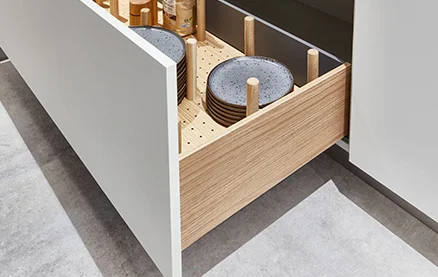 Holzstäbe sichern Teller in SENSO 488 Alpinweiß. Stilvolle Kombination aus Holz und Front für Ordnung und Schutz im Alltag.