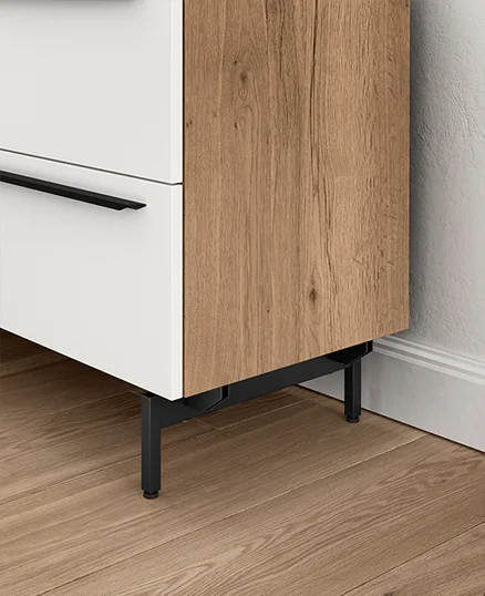 Moderne zweifarbige Schrank mit einer weißen Schublade und einer Holzfurniertür, mit eleganten schwarzen Griffen und Beinen, auf einem Fischgrätparkettboden.