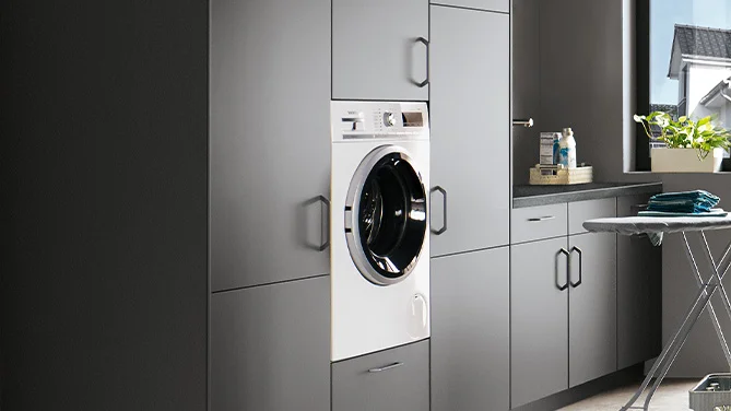 Integrated washing machine in nobilia utility room with TOUCH 334 front in stone gray super matt. Perfectly integrated into a functional cabinet system for modern household solutions.