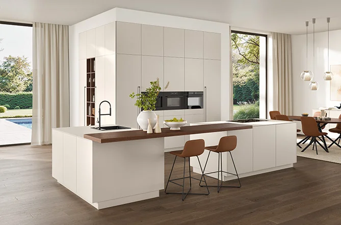 Moderne Küche mit Kochinsel, Barplatte in Holzoptik und Fronten in Sand Perfect matt Lack – klar, wohnlich, offen.
