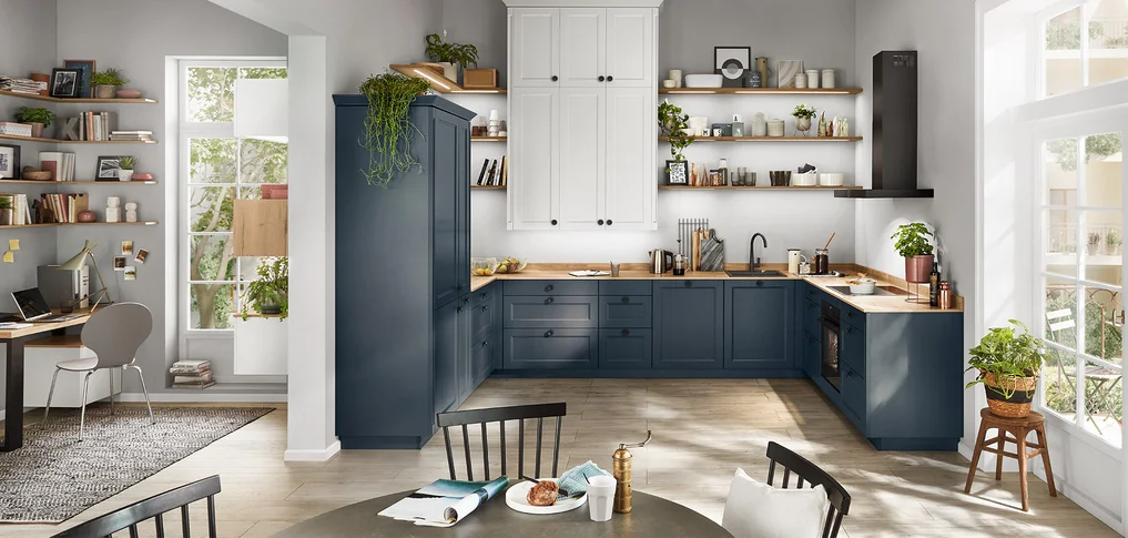 Moderne Landhausküche mit Herd und Kochbereich in nobilia Front Cascada 778 in Fjordblau. Die Küche bietet eine elegante Kombination aus blauen Unterschränken, offenen Regalen, weißen Oberschränken und integriertem Arbeitsplatz