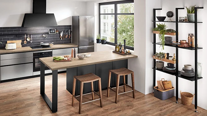 Modern nobilia kitchen with Inox 216 front and striking black extractor hood in industrial style. The open room design combines a stainless steel look with warm wood decor and a functional shelving system.