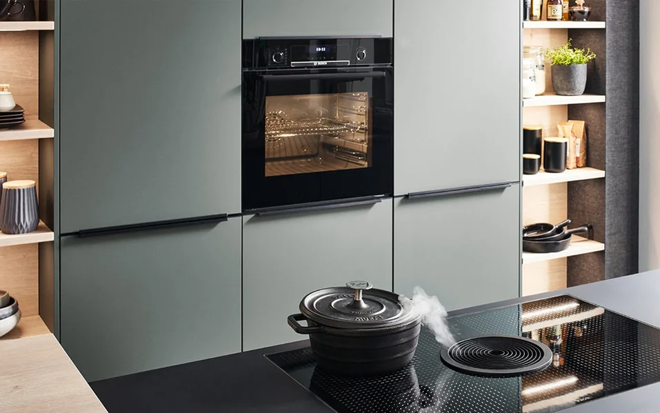 Moderne Küche mit matten Fronten, offenen Regalen und Kochfeldabzug mit dampfendem Topf als Teaser für innovative Produkt Highlights von nobilia.