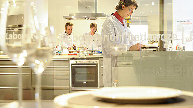 nobilia Labor mit drei Fachkräften in weißen Kitteln im Jahr 2009, die in einer modernen Küche arbeiten und verschiedene Zutaten vorbereiten.