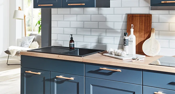 Blaue Landhausküche mit weißer Nischenverkleidung in Steinoptik.