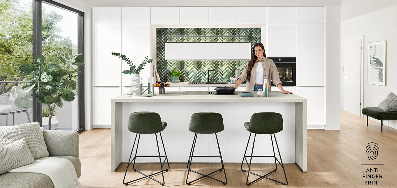 Sally in moderner Anti-Fingerprint Küche mit weißer Front, Kochinsel und grünem Fliesenspiegel in Fischgrätoptik.