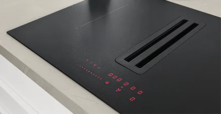Detailansicht Xtra Hob Kochfeld in Schwarz matt mit rotem Touchdisplay und integriertem Dunstabzug auf heller Arbeitsplatte.
