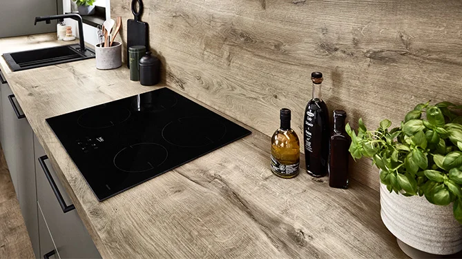 Elegant nobilia kitchen with Laser 461 front in a modern design. The black glass ceramic hob is integrated flush into the wooden worktop and forms the heart of the stylish kitchen unit.
